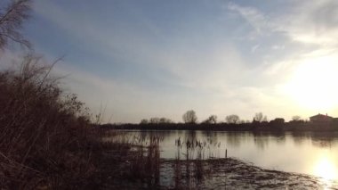 Gün batımında nehir kıyısında güzel bir manzara. Nehrin üzerinde gün doğumu, kıyıya yakın, 4k. Nehirde güzel bir kış akşamı. Buz ilkbaharda erir. Suyun üzerinde erime.