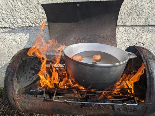 Cooking in a pot on the fire in the spring of red fish soup. Black bowler hat with ear on the fire near the lake. a wood-fired soup trough. delicious fish soup on the fire