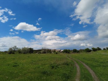 Yollu ve bulutlu bir manzara. Uzağa giden toprak yol. Kötü bir yolda araba kullanmak.