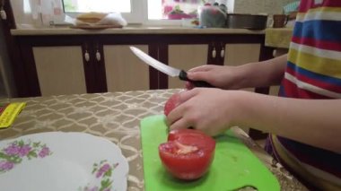 Domates dilimliyorum. Yemek salatası. Çocuk yemek yapıyor. ev mutfağı