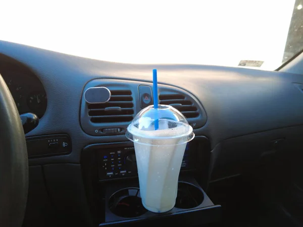 車の中でミルクシェイク ミルクセーキとストロー付きのガラス 車の中で牛乳を飲む — ストック写真
