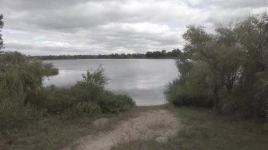 Nehrin kıyısına yürü. Su ve bulutlu bir manzara. Açık hava sporları. 4k video. nötr renk.