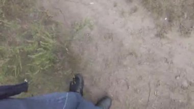 Erkek bacakları. Kot pantolon. Siyah ayakkabılar. Patika boyunca yürü. Adam serbest kalacak. Birinci şahıs görüşü. 4k video