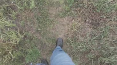 Erkek bacakları. Kot pantolon. Siyah ayakkabılar. Patika boyunca yürü. Adam serbest kalacak. Birinci şahıs görüşü. 4k video