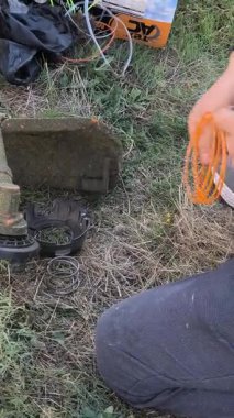 Bir adam çim biçme makinesini tamir eder. Bir adam manuel çim biçme makinesini tamir eder. 4K video görüntüleri.