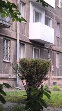 Çok katlı apartmanı, balkonları, ağaçları ve bankı olan şehir avlusu. Beton ve yeşillik karışımı, tipik bir Doğu Avrupa mahallesinde günlük yaşamı yakalıyor..