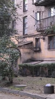 Çok katlı apartmanı, balkonları, ağaçları ve bankı olan şehir avlusu. Beton ve yeşillik karışımı, tipik bir Doğu Avrupa mahallesinde günlük yaşamı yakalıyor..