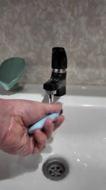 Elde sabun ve musluk suyu. Elinde mavi sabun var. Kadın sabunlu köpüklerle ellerini yıkıyor ve su da yavaş çekimde 4K seçici odaklanıyor. Yavaş çekim videosu.