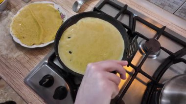 Kızartma tavasında gözleme. Yetenekli bir şef lezzetli bir krep pişirir, tavada kızartır, yakın plan, kırpılmış yan görüş, yavaş çekim. Bir adam evde krep kızartır. Şeye göre yemek pişirmek...