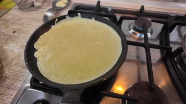 Kızartma tavasında gözleme. Yetenekli bir şef lezzetli bir krep pişirir, tavada kızartır, yakın plan, kırpılmış yan görüş, yavaş çekim. Bir adam evde krep kızartır. Şeye göre yemek pişirmek...