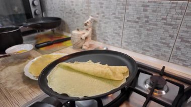 Kızartma tavasında gözleme. Yetenekli bir şef lezzetli bir krep pişirir, tavada kızartır, yakın plan, kırpılmış yan görüş, yavaş çekim. Bir adam evde krep kızartır. Şeye göre yemek pişirmek...