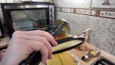 Kızartma tavasında gözleme. Yetenekli bir şef lezzetli bir krep pişirir, tavada kızartır, yakın plan, kırpılmış yan görüş, yavaş çekim. Bir adam evde krep kızartır. Şeye göre yemek pişirmek...