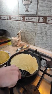 Kızartma tavasında gözleme. Yetenekli aşçı lezzetli krepler pişiriyor, tavada kızartıyor, yakın çekimde yavaş çekimde kırpılıyor. Bir adam evde krep kızartır. Dikey 4K video