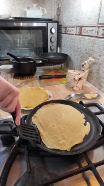 Kızartma tavasında gözleme. Yetenekli aşçı lezzetli krepler pişiriyor, tavada kızartıyor, yakın çekimde yavaş çekimde kırpılıyor. Bir adam evde krep kızartır. Dikey 4K video