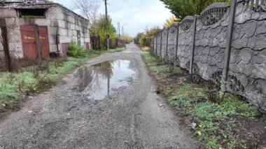 Su birikintileri yolda, ağır çekimde. Sonbahar yağmur damlaları asfalttaki büyük bir su birikintisine düşer ve caddeyi sel basar. Renkli sonbahar yaprakları rüzgarlı bir günde yoldaki bir su birikintisine eser.