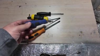 Tornavida elinde. Kapalı alanda DIY ahşap mobilya monte ederken, siyah erkek eli tornavidayla vidaları tamir ederken yakın plan. Küçük Tornavidalar.