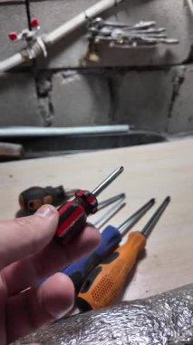 Tornavida elinde. Kapalı alanda DIY ahşap mobilya monte ederken, siyah erkek eli tornavidayla vidaları tamir ederken yakın plan. Küçük Tornavidalar.