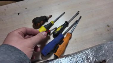 Tornavida elinde. Kapalı alanda DIY ahşap mobilya monte ederken, siyah erkek eli tornavidayla vidaları tamir ederken yakın plan. Küçük Tornavidalar.