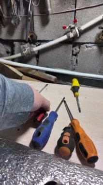Tornavida elinde. Kapalı alanda DIY ahşap mobilya monte ederken, siyah erkek eli tornavidayla vidaları tamir ederken yakın plan. Küçük Tornavidalar.