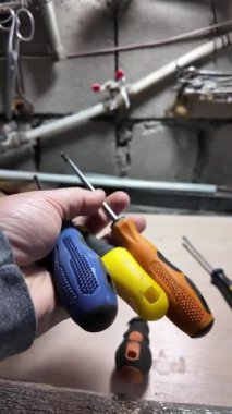 Tornavida elinde. Kapalı alanda DIY ahşap mobilya monte ederken, siyah erkek eli tornavidayla vidaları tamir ederken yakın plan. Küçük Tornavidalar.