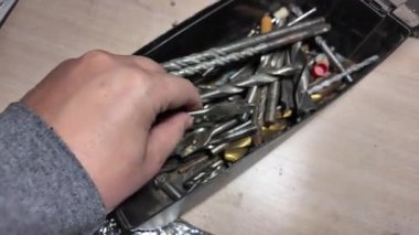 Matkap uçları. Elektrikli matkapla beyaz bir duvarı delmeye yakın plan. İnşaata odaklan. İnşaat, yenileme, DIY projeleri, inşaat aracı reklamcılığı, eğitim.