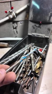 Matkap uçları. Elektrikli matkapla beyaz bir duvarı delmeye yakın plan. İnşaata odaklan. İnşaat, yenileme, DIY projeleri, inşaat aracı reklamcılığı, eğitim.