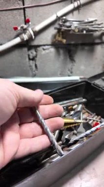 Matkap uçları. Elektrikli matkapla beyaz bir duvarı delmeye yakın plan. İnşaata odaklan. İnşaat, yenileme, DIY projeleri, inşaat aracı reklamcılığı, eğitim.