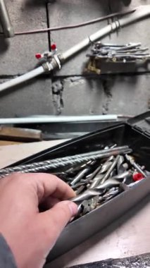 Matkap uçları. Elektrikli matkapla beyaz bir duvarı delmeye yakın plan. İnşaata odaklan. İnşaat, yenileme, DIY projeleri, inşaat aracı reklamcılığı, eğitim.