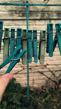 Clothespins on a clothesline. A person opens a clothespin with his fingers. Colorful clothespins hang together on an outdoor clothesline during the rain.