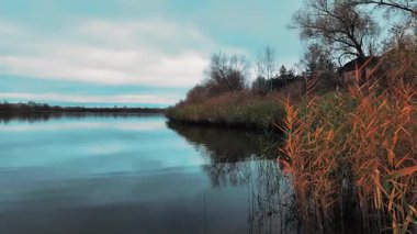Gölü ve mavi suyu olan güzel bir sonbahar manzarası. Retro-stil manzara. Sıra dışı renkler. Gölde gün batımı. 4K 60fps. Sinematik görüntüler.