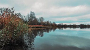 Gölü ve mavi suyu olan güzel bir sonbahar manzarası. Retro-stil manzara. Sıra dışı renkler. Gölde gün batımı. 4K 60fps. Sinematik görüntüler.