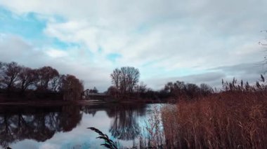 Gölü ve mavi suyu olan güzel bir sonbahar manzarası. Retro-stil manzara. Sıra dışı renkler. Gölde gün batımı. 4K 60fps. Sinematik görüntüler.