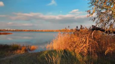 Beautiful autumn landscape with a lake and blue water. Landscape in cinematic colors. Sunset on the lake. 4K 60fps.
