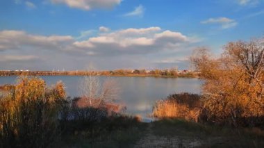 Beautiful autumn landscape with a lake and blue water. Landscape in cinematic colors. Sunset on the lake. 4K 60fps.