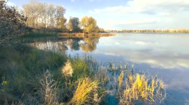 Beautiful autumn landscape with a lake and blue water. Retro-style landscape. Unusual colors. Sunset on the lake. 4K 60fps.
