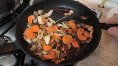 Kızartma tavasında sebze kızartan biri. Kızartma tavasında sebze karıştıran biri spagetti bolonez yaparken ya da tavada tahta kaşıkla pizza sosu yaparken. Kızarmış tavada sebze kızartan bir şef..