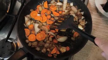 Kızartma tavasında sebze kızartan biri. Kızartma tavasında sebze karıştıran biri spagetti bolonez yaparken ya da tavada tahta kaşıkla pizza sosu yaparken. Kızarmış tavada sebze kızartan bir şef..