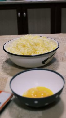 Mutfak masasında hamuru karıştıran eller, ev yapımı pişirme işlemi un ve rendelenmiş malzemeler, yakın plan yemek hazırlama sahnesi kırsal ev yemekleri ve geleneksel mutfakları gösteriyor..