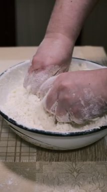 Mutfak masasında hamuru karıştıran eller, ev yapımı pişirme işlemi un ve rendelenmiş malzemeler, yakın plan yemek hazırlama sahnesi kırsal ev yemekleri ve geleneksel mutfakları gösteriyor..