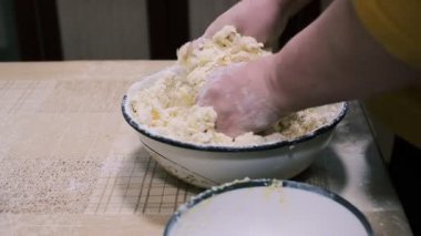 Mutfak masasında hamuru karıştıran eller, ev yapımı pişirme işlemi un ve rendelenmiş malzemeler, yakın plan yemek hazırlama sahnesi kırsal ev yemekleri ve geleneksel mutfakları gösteriyor..