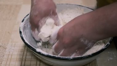 Mutfak masasında hamuru karıştıran eller, ev yapımı pişirme işlemi un ve rendelenmiş malzemeler, yakın plan yemek hazırlama sahnesi kırsal ev yemekleri ve geleneksel mutfakları gösteriyor..