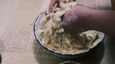 Mutfak masasında hamuru karıştıran eller, ev yapımı pişirme işlemi un ve rendelenmiş malzemeler, yakın plan yemek hazırlama sahnesi kırsal ev yemekleri ve geleneksel mutfakları gösteriyor..