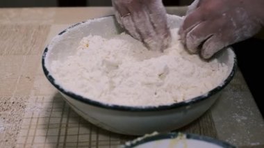 Mutfak masasında hamuru karıştıran eller, ev yapımı pişirme işlemi un ve rendelenmiş malzemeler, yakın plan yemek hazırlama sahnesi kırsal ev yemekleri ve geleneksel mutfakları gösteriyor..