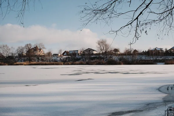 Donmuş göl manzarası, karla kaplı buzlar, sazlıklar ve mavi gökyüzü altındaki kış kıyı şeridi, sakin mevsimsel manzara soğuk havayı, durgun su kenarlarını ve kırsal kış atmosferini gösteriyor..