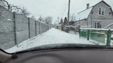 Kar fırtınasında karlı Rus köyünün içinden geçmek. Karla kaplı yol, ön cama düşen ağır kar taneleri, karlı caddenin ortasında duran başıboş bir köpek. Konforlu araba iç görünümü.