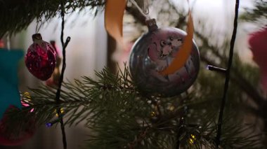 Çok güzel dekore edilmiş bir Noel ağacının, klasik cam takılarıyla, mavi süslemelerle el boyaması karlı kış sahneleriyle, renkli ışıklarla, şenlikli bokeh, kurdele ve çam dallarıyla yakın çekimi..