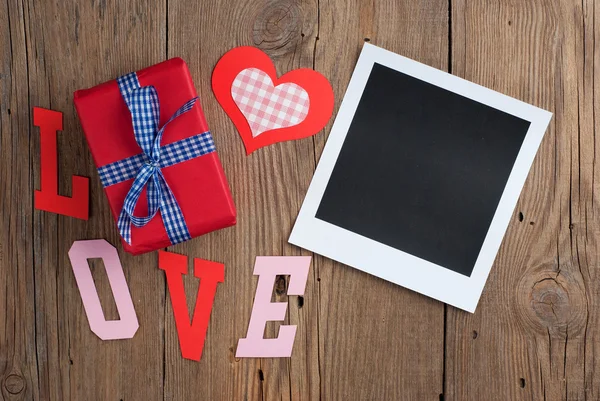 Instant photo with gift and hearts — Stock Photo, Image
