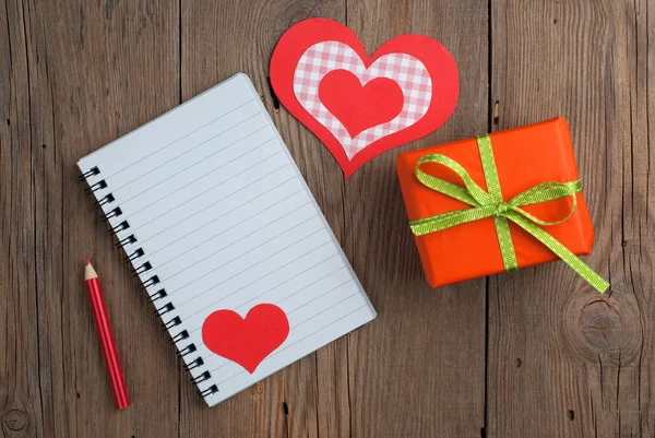Cuaderno con regalo, lápiz y corazones — Foto de Stock