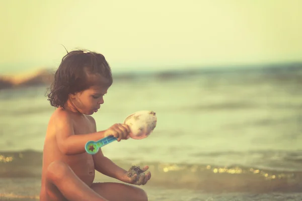 Flicka spelar med spade i sand på stranden. Mjukt fokus — Stockfoto