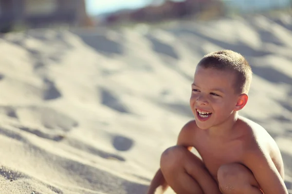 Pojke ensam i sand på stranden med vackert leende — Stockfoto
